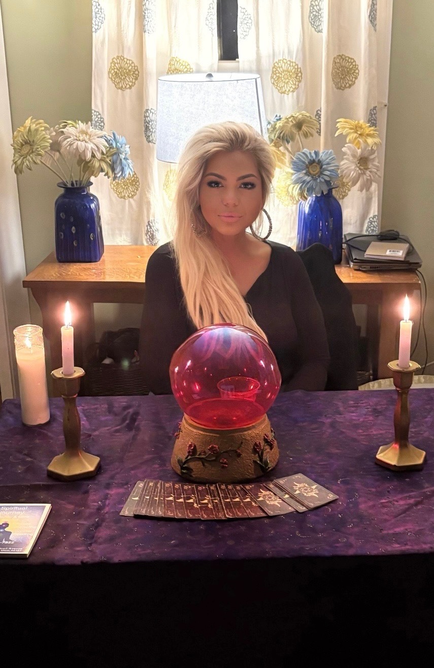 The psychic at her candlelit reading table with crystal ball and tarot cards